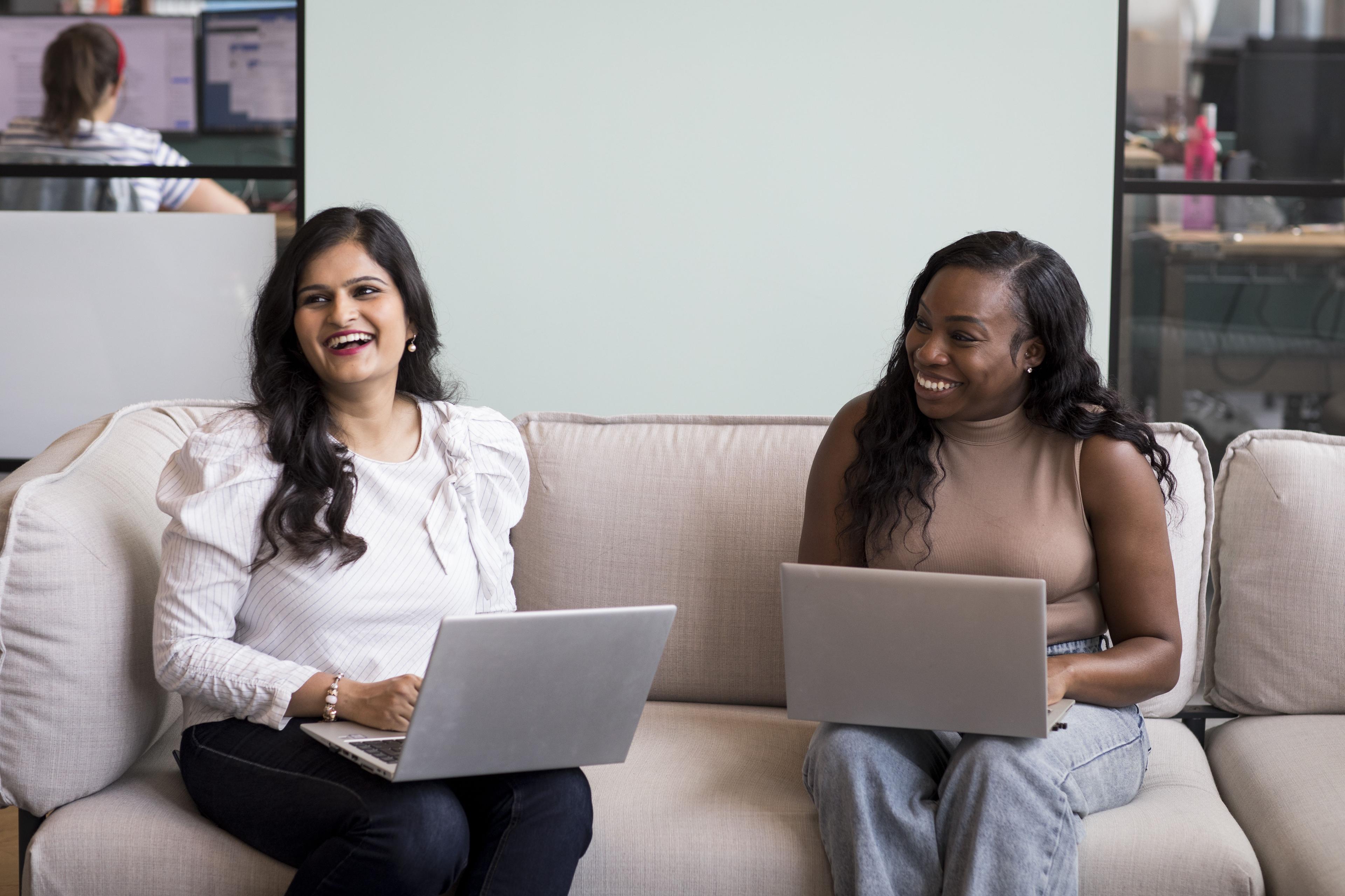 Two women with laptops smiling