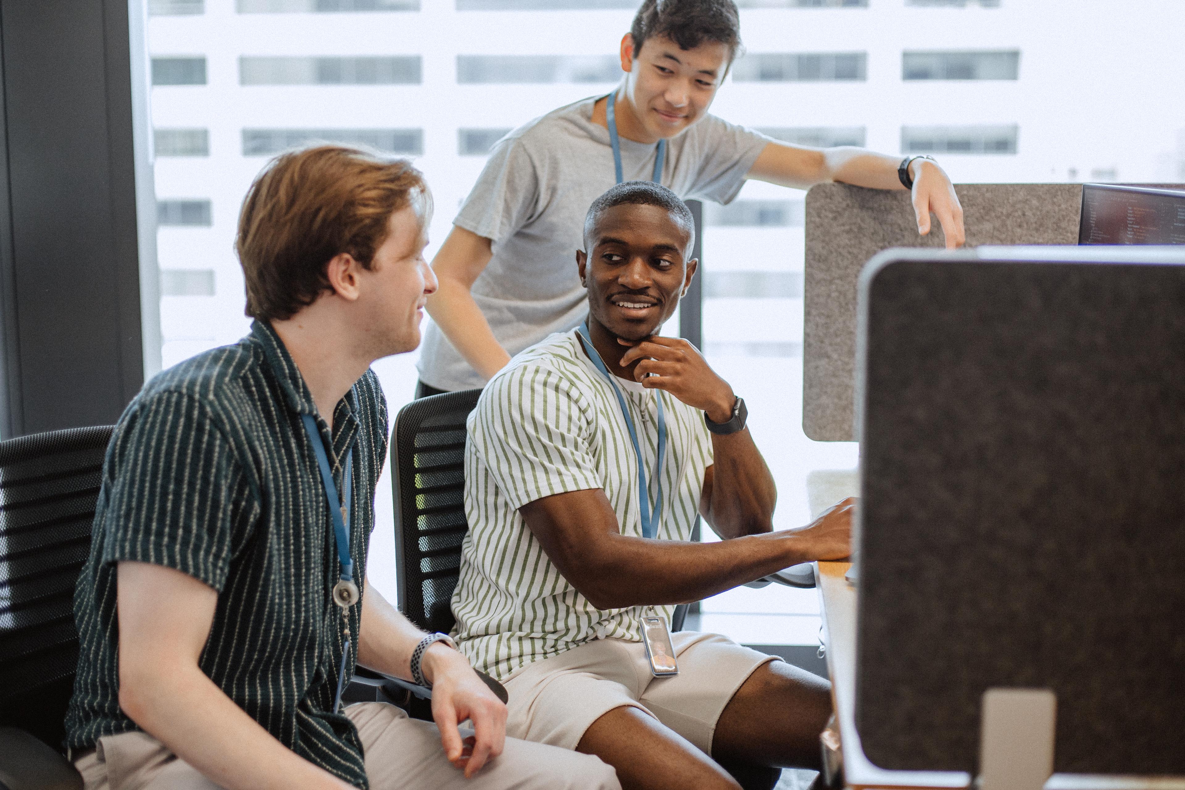 Three men gathered around a computer.